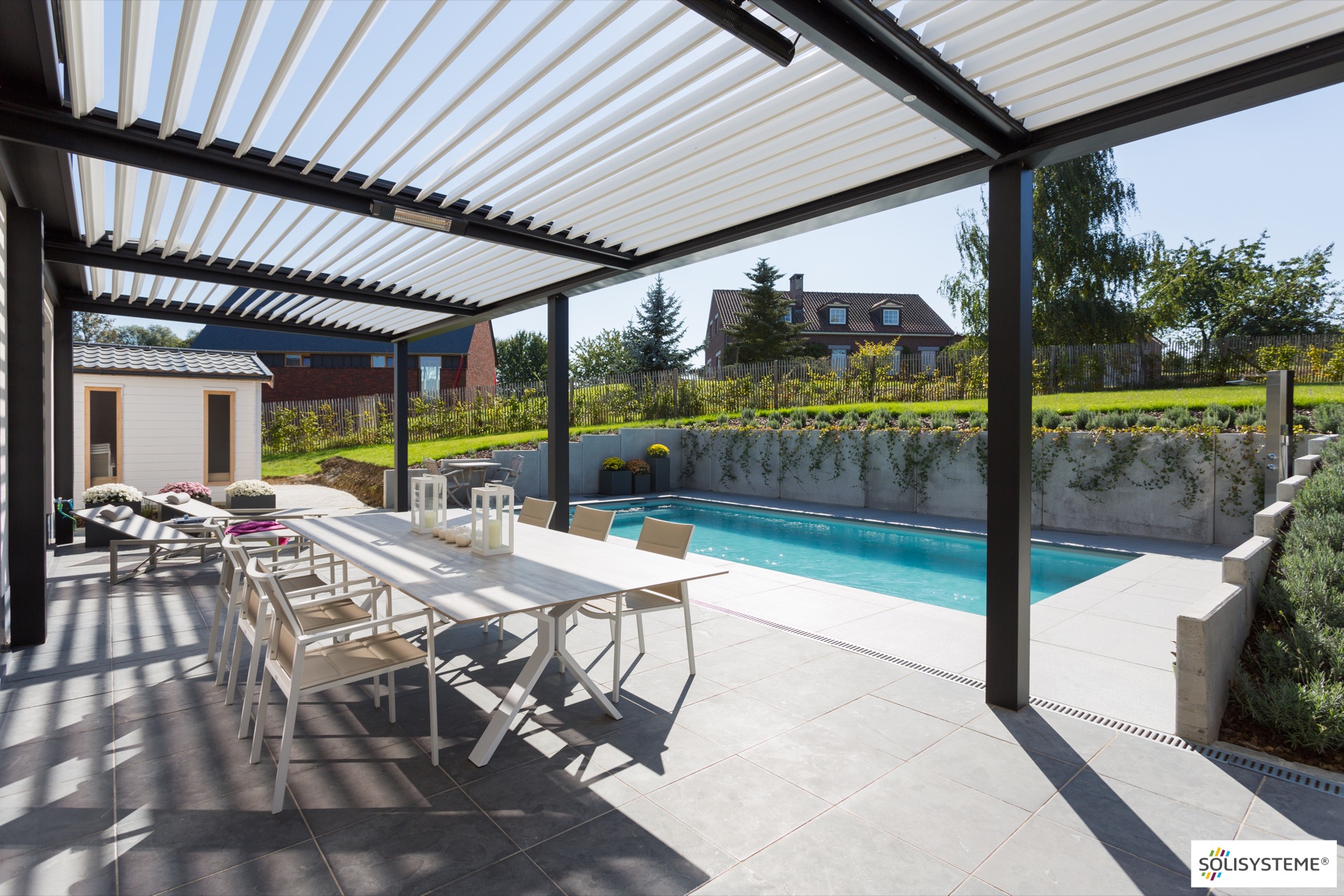 Pergola bioclimatique à lames orientables au bord d’une piscine